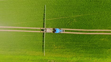 top down drone view of tractor spraying crops in sunny latvia with sharp lines
