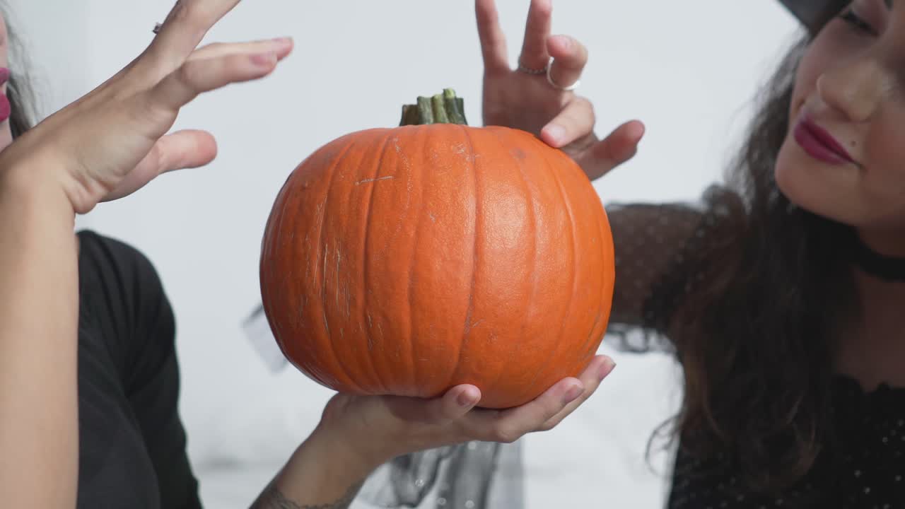 Two Witches Examining a Pumpkin