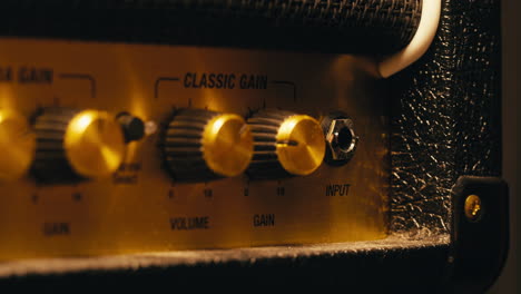 close-up of plugging a jack into a guitar amplifier and turning up the volume knob, live concert show, playing music on guitar tube amplifier.