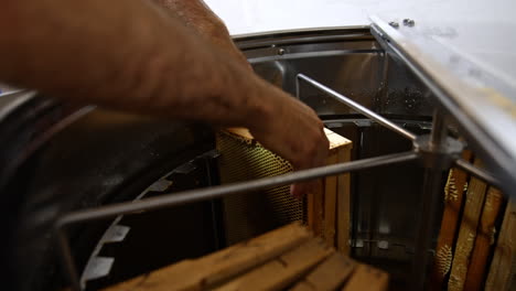 filling the electric honey extracting machine with wooden frames. male hands place the frames close to each other in the centrifuge equipment.