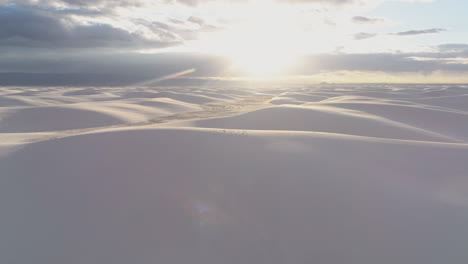 antena de 4k que viene sobre una duna para revelar un vasto campo de dunas de arena blanca al amanecer
