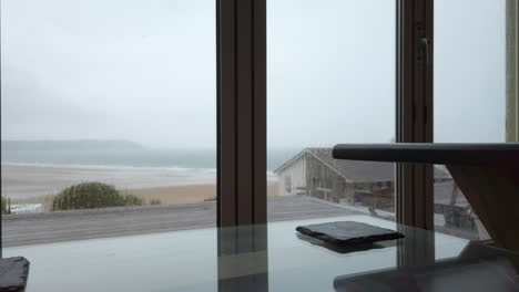 raindrops falling against glass doors with a coffee table in foreground