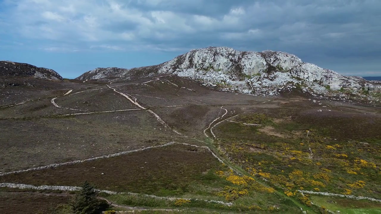 Luftfoto af den barske Holyhead bjergtop over en solrig, landlig hede med vandresti.