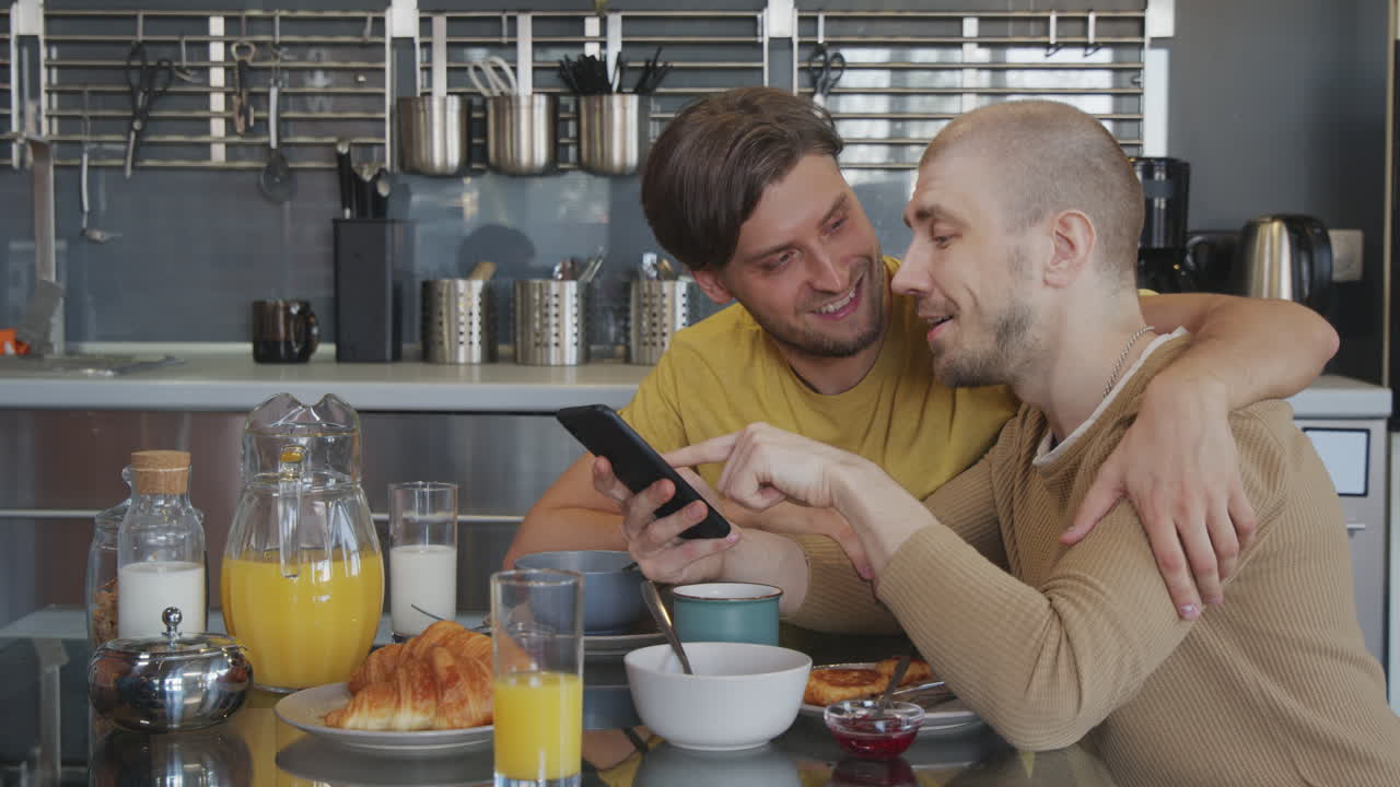 Gay Couple with Mobile Phone Chatting during Breakfast