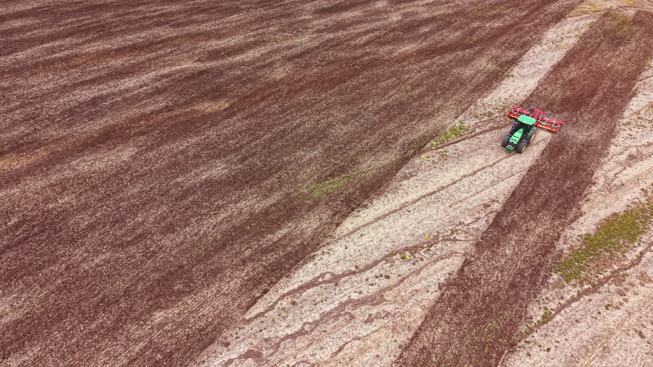 Trattore che ara il terreno marrone in un campo agricolo in campagna durante il giorno.