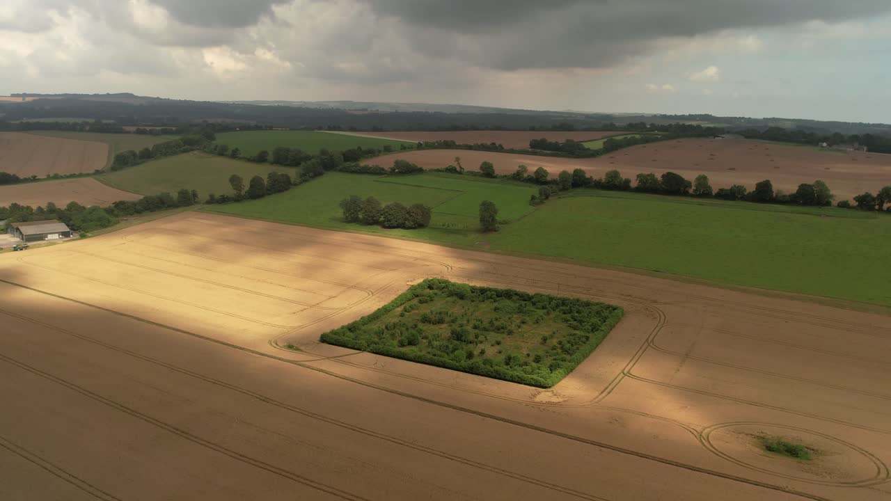 Sunlight breaking through dense rain clouds casting shadows on farmland aerial push in view