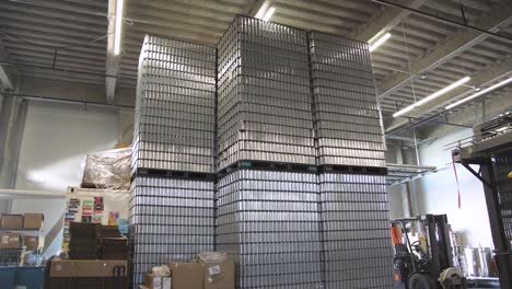 stacked pallets of empty aluminum beer cans in brewery warehouse