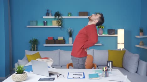 Young-businessman-showing-how-to-exercise-in-his-Home-Office.-He-does-standing-back-exercises.