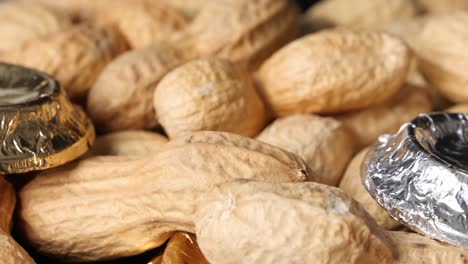 Heap-of-peanuts-and-several-wrapped-chocolate-treats-on-table