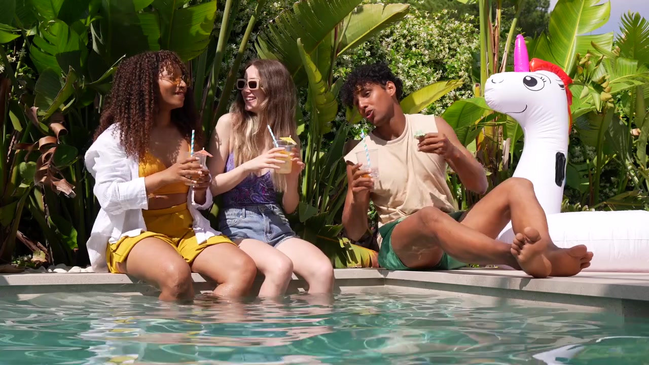 Amici felici multietnici che si rilassano a bordo piscina con drink
