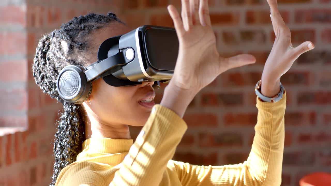 Afrikansk-amerikansk afslappet forretningskvinde bruger VR-headset på et solrigt kontor, slow motion.