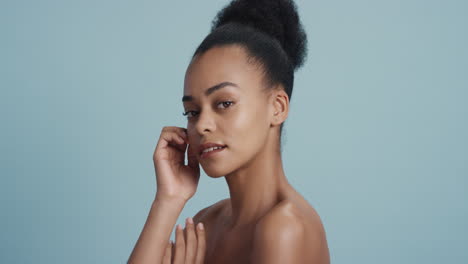 portrait healthy young woman touching face with hand caressing smooth skin complexion enjoying soft natural beauty on blue background skincare concept