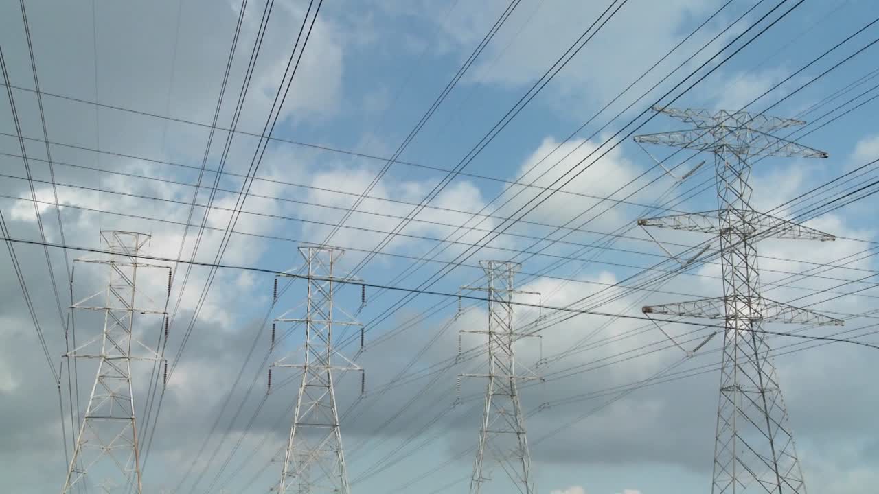 Time lapse of clouds moving behind high tension wires and power lines 1