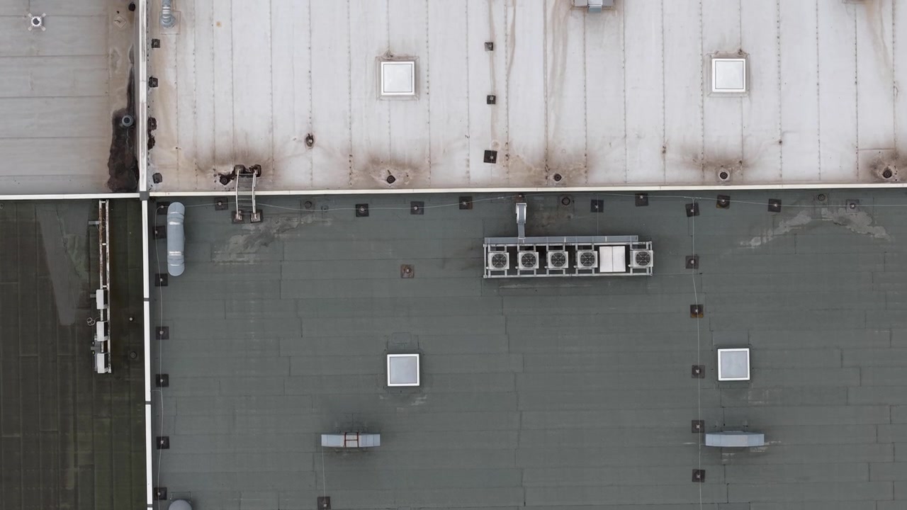 Aerial perspective of a building's rooftop showcasing various HVAC units and mechanical equipment against a gray surface.