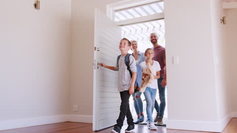 disparo en cámara lenta de la familia abriendo la puerta y caminando en el salón vacío de la nueva casa