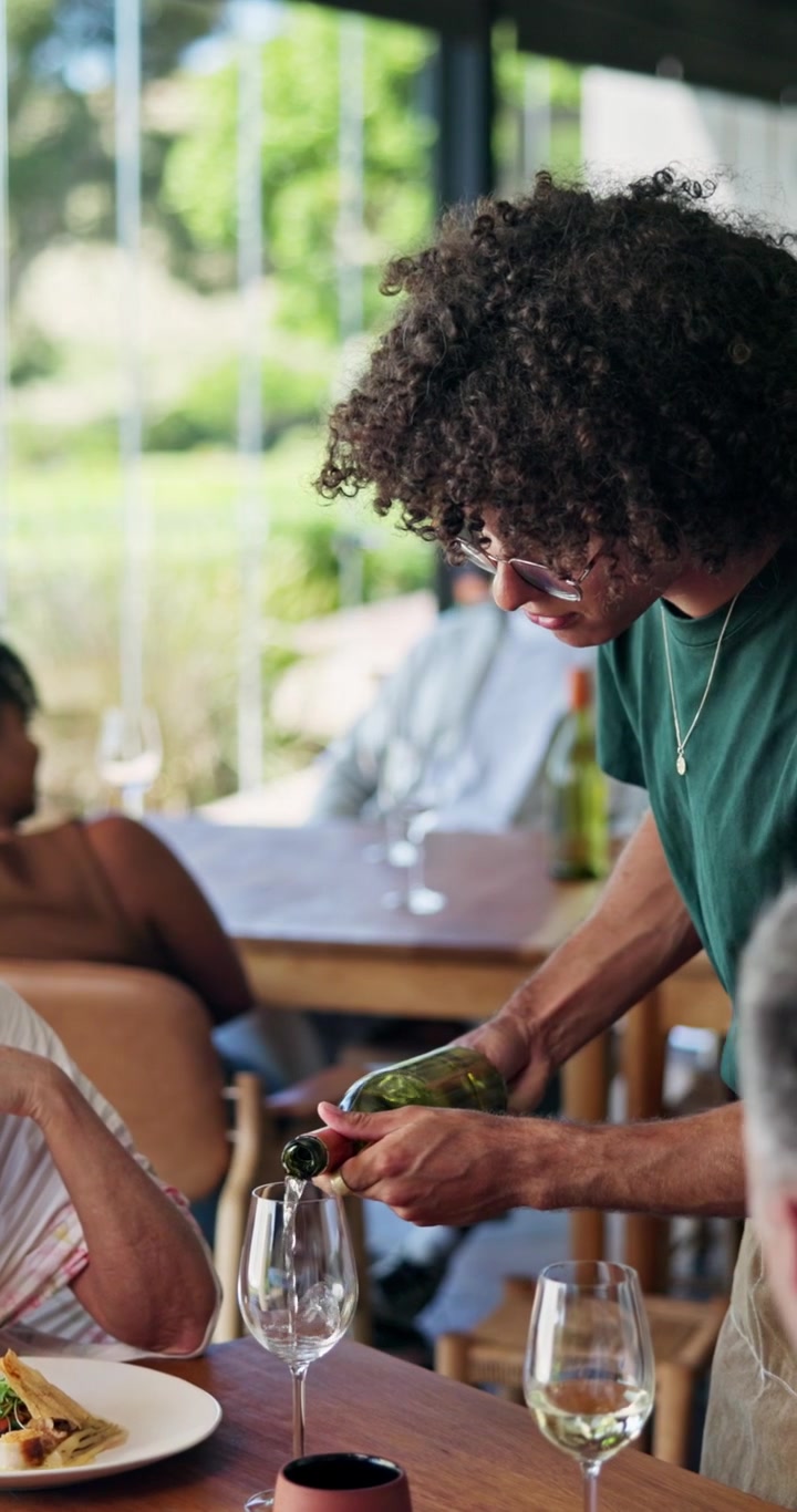 Waiter Pouring White Wine for Customers in a Restaurant