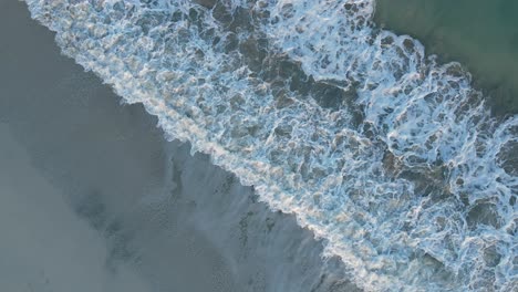 uae: aerial view of waves breaks on the beach, bird's eye view of ocean waves crashing and foaming against the empty shore, rough sea view