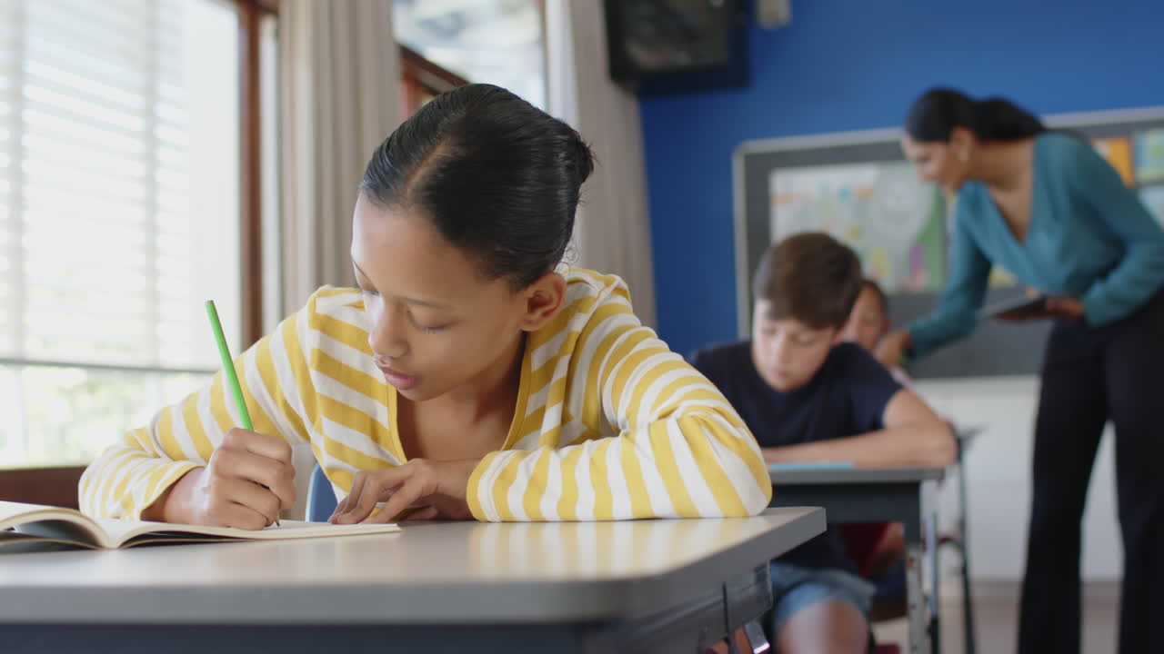 In school, girl writing in notebook at desk, focusing on classroom work