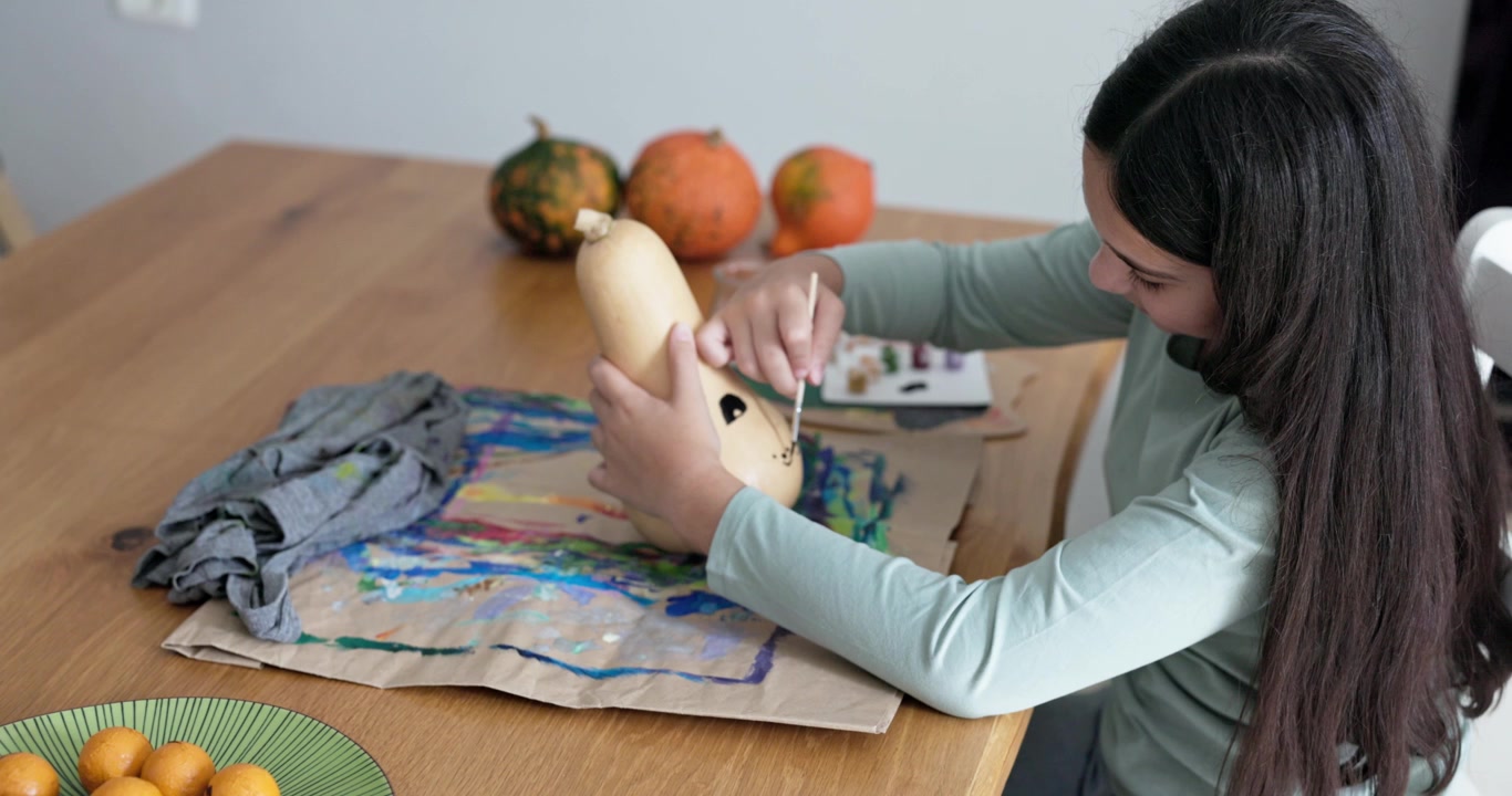Young Girl Painting a Butternut Squash at Home