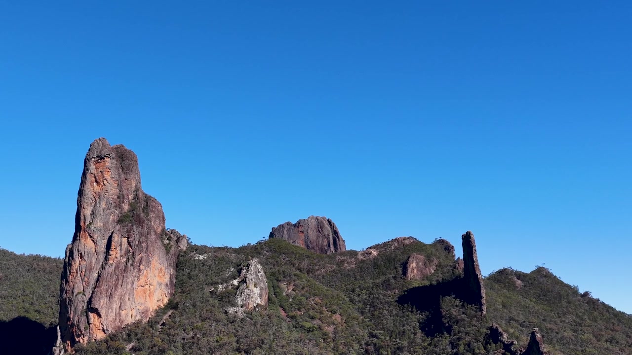 Inquadratura ampia della formazione rocciosa The Breadknife sotto un cielo azzurro sereno nel Parco Nazionale di Warrumbungle.