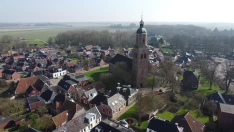 un dron captura el pueblo de eenrum con la torre de la iglesia a principios de mayo, mostrando una vegetación exuberante y un paisaje tranquilo