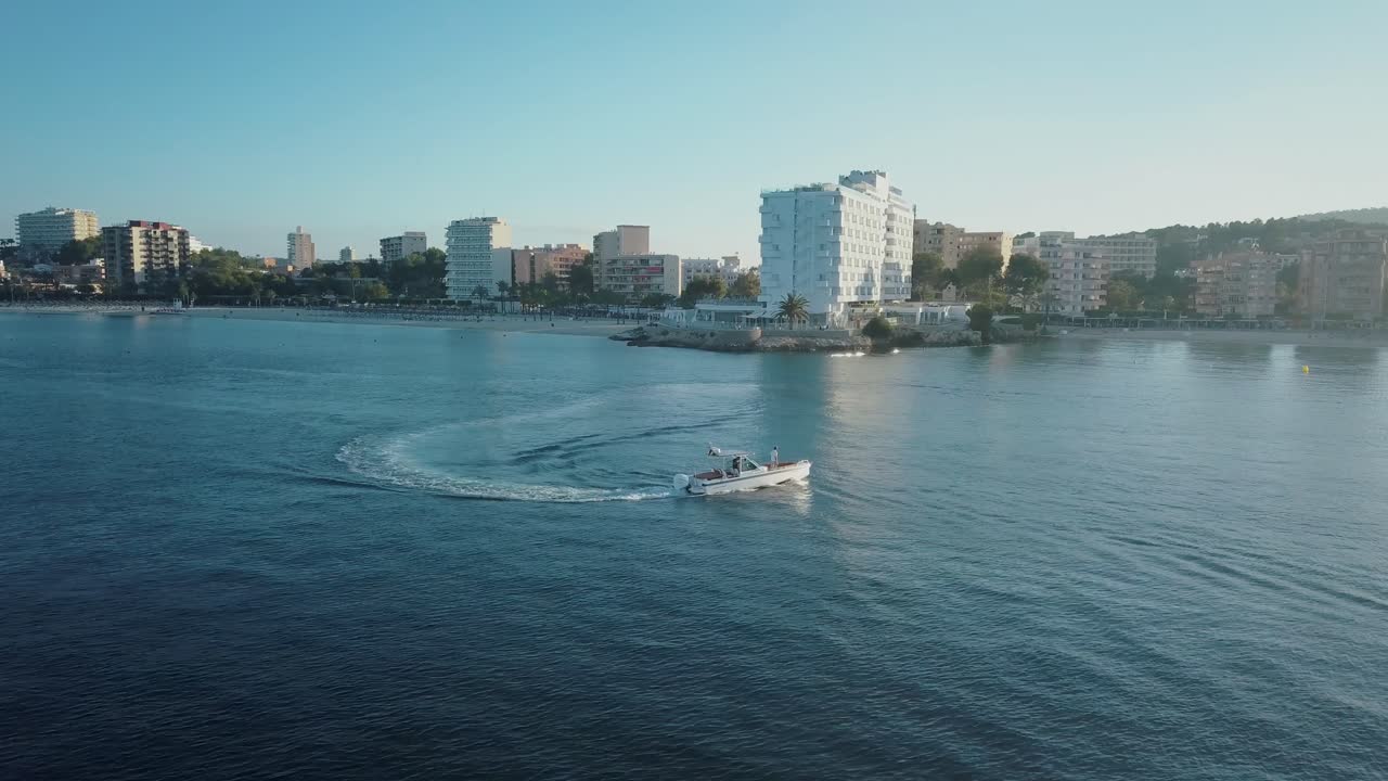 Drone footage in 4k of boat cruising in calm water in Mallorca - Palmanova beach - Magaluf at Sunset - Mediterranean Sea