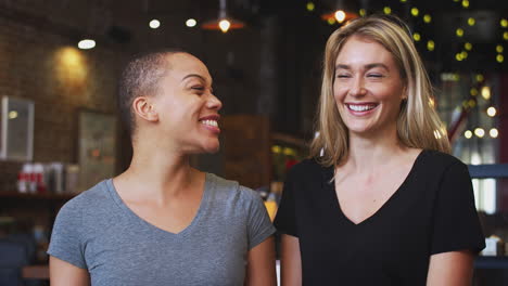 portrait of two female coffee shop owners standing at sales desk