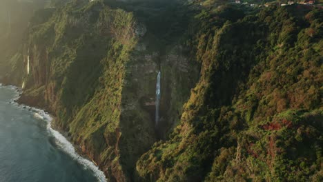 amanecer iluminando la línea de la gran costa de madeira con cascada, hora dorada, antena