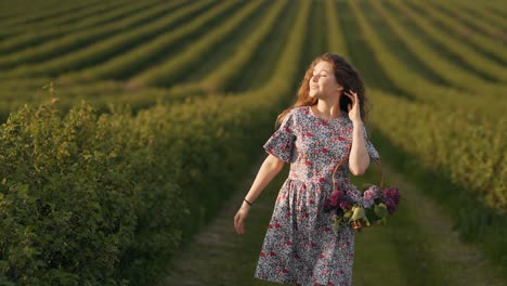 beautiful curly red-haired girl in a field with a basket of lilac flowers