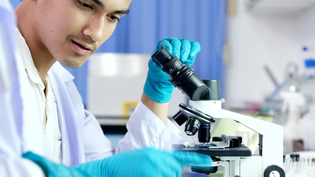 Male research scientist analyzing microscope slides in research lab. 4k Resolution.
