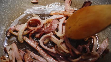 frying bacon slices on a pan in cooking oil