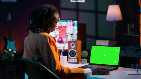 African american young woman looks at laptop with greenscreen