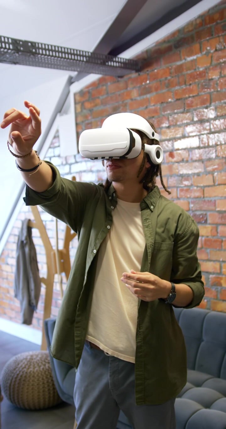 Video verticale: Uomo afroamericano con visore VR che reagisce a un input, si protende e scorre in un loft.