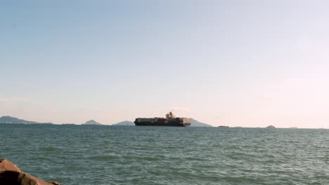 Distant-view-of-maritime-cargo-ship-transporting-intermodal-containers-through-the-serene-waters-of-the-Panama-Canal-during-the-day-with-a-clear-blue-sky-and-mild-winds-cruising-to-the-pacific-ocean