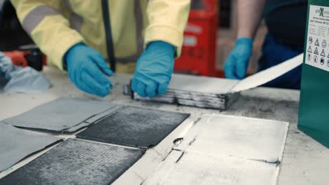 close up how carbon and seperator layers of a big battery get layed down across the table by two workers in terms of quality control an condition check