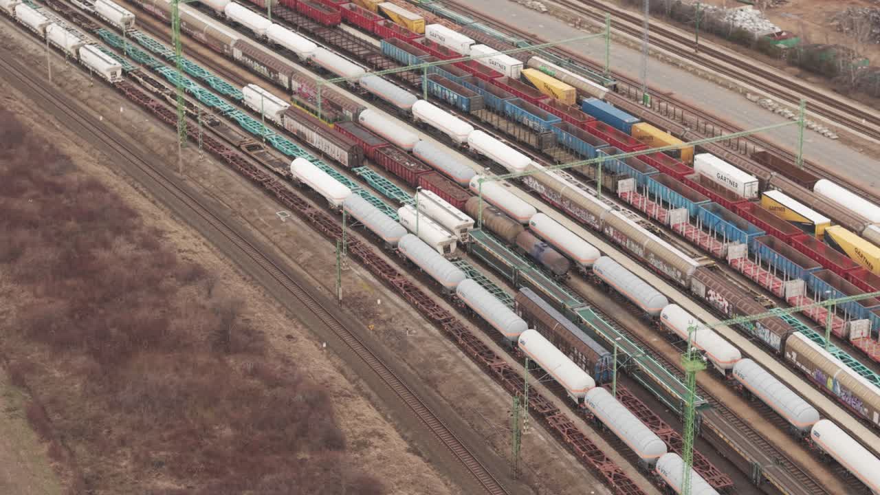 Luftaufnahme eines großen Rangierbahnhofs, gefüllt mit Güterzügen, Kesselwagen und bunten Frachtcontainern.