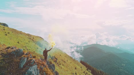 the man stands on the mountain edge with a colored hand smoke