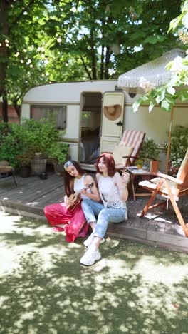 two women playing ukulele in a summer camping setting