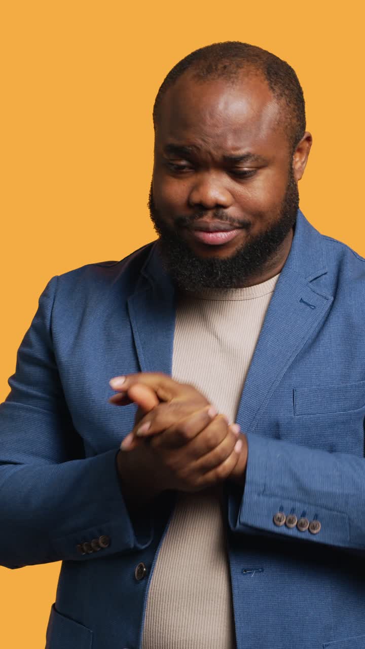 Vertical video Man covering mouth in disbelief, feeling upset by events, studio background