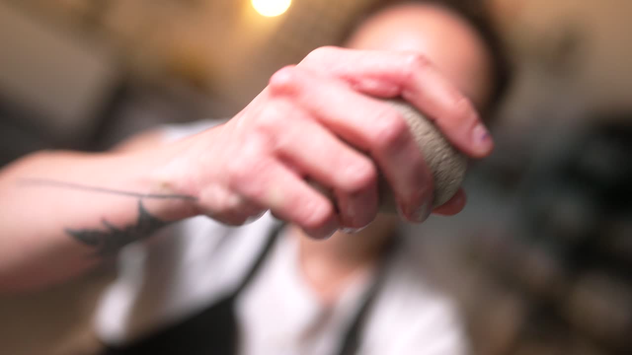 Close-up shot of a hand squeezing a sponge while doing pottery, water dripping on the clay in slow motion