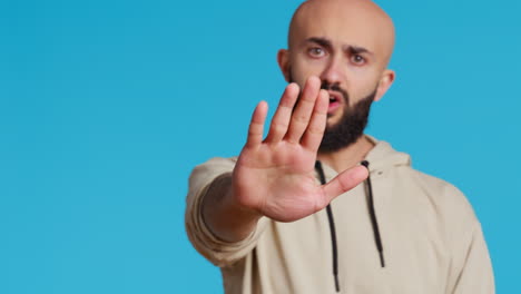 middle eastern man raises palm and says no in studio