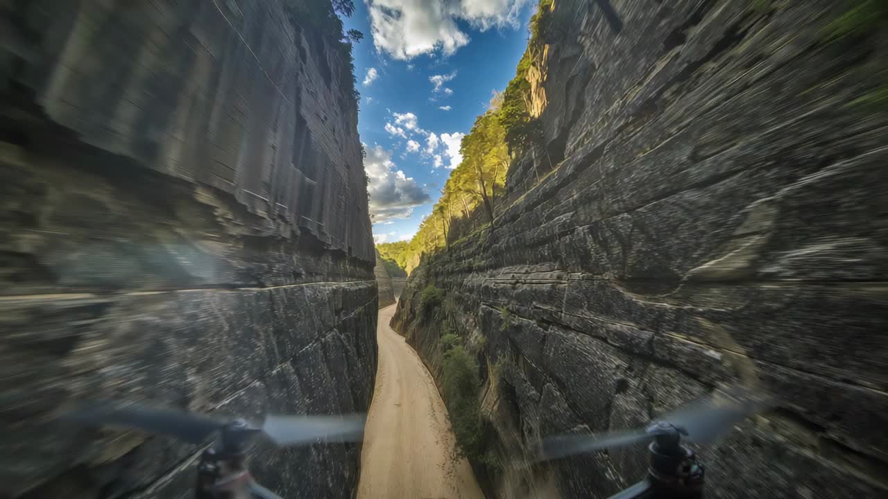 Drone con telecamera volante che entra in uno stretto canyon roccioso, che percorre una strada sterrata, mostrando la sfocatura delle eliche
