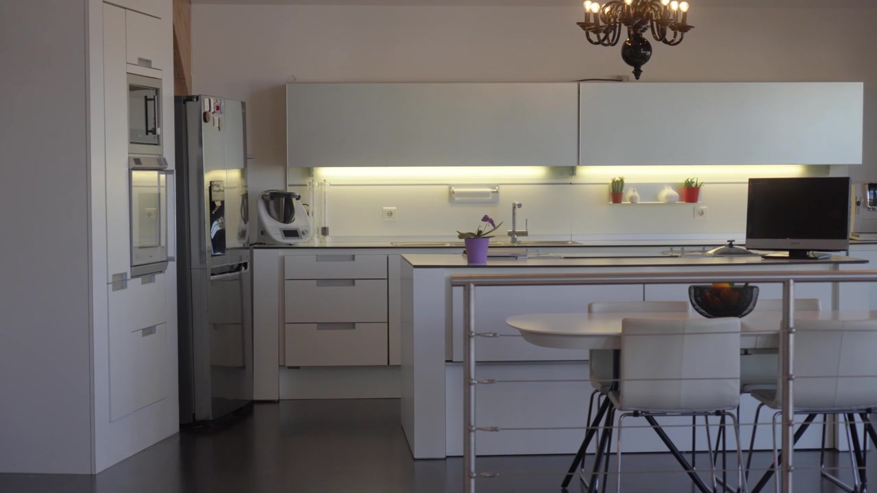 Tomada ampla de uma cozinha moderna com ilha, área de jantar, eletrodomésticos e decoração