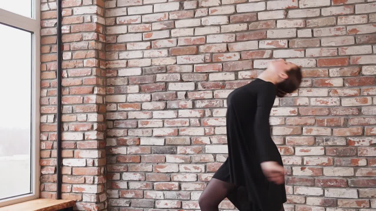 검은 드레스를 입은 여성 댄서가 스튜디오에서 연습하고 있습니다.