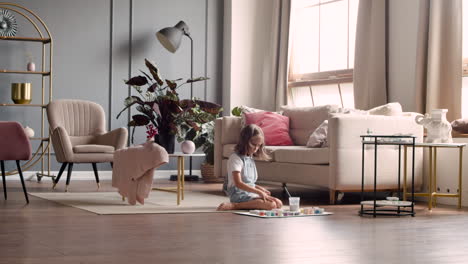 wide view of blonde girl picking out color paints in living room