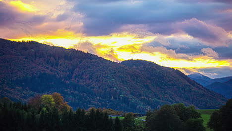 Zeitraffer-Von-Wolken,-Die-Sich-Bei-Sonnenuntergang-Von-Rechts-Nach-Links-über-Den-Baumbedeckten-Berg-In-Den-Alpen-Bewegen