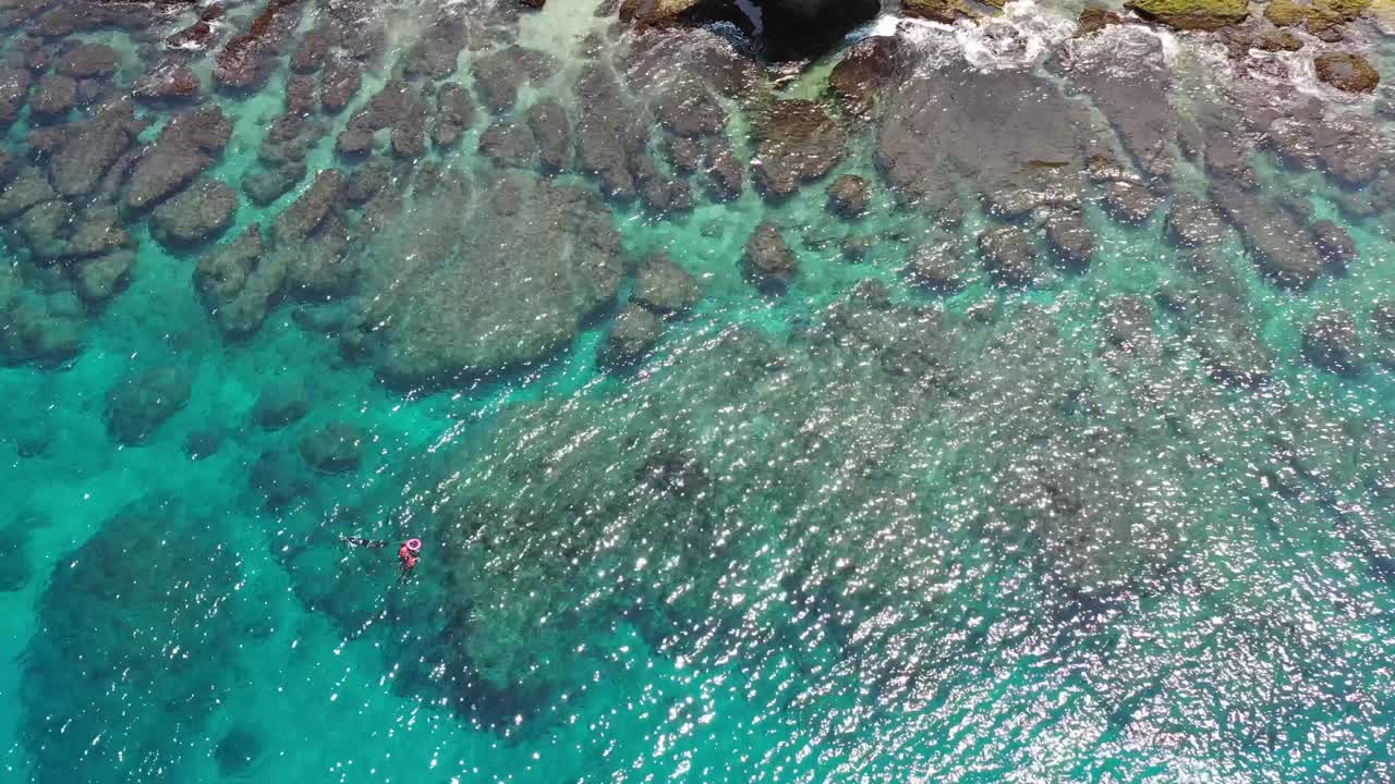 tiro de seguimiento aéreo hacia abajo mirando el hermoso mar azul claro y el arrecife oceánico a la luz del día en la isla xiaoliuqiu lambai, condado de pingtung, taiwán