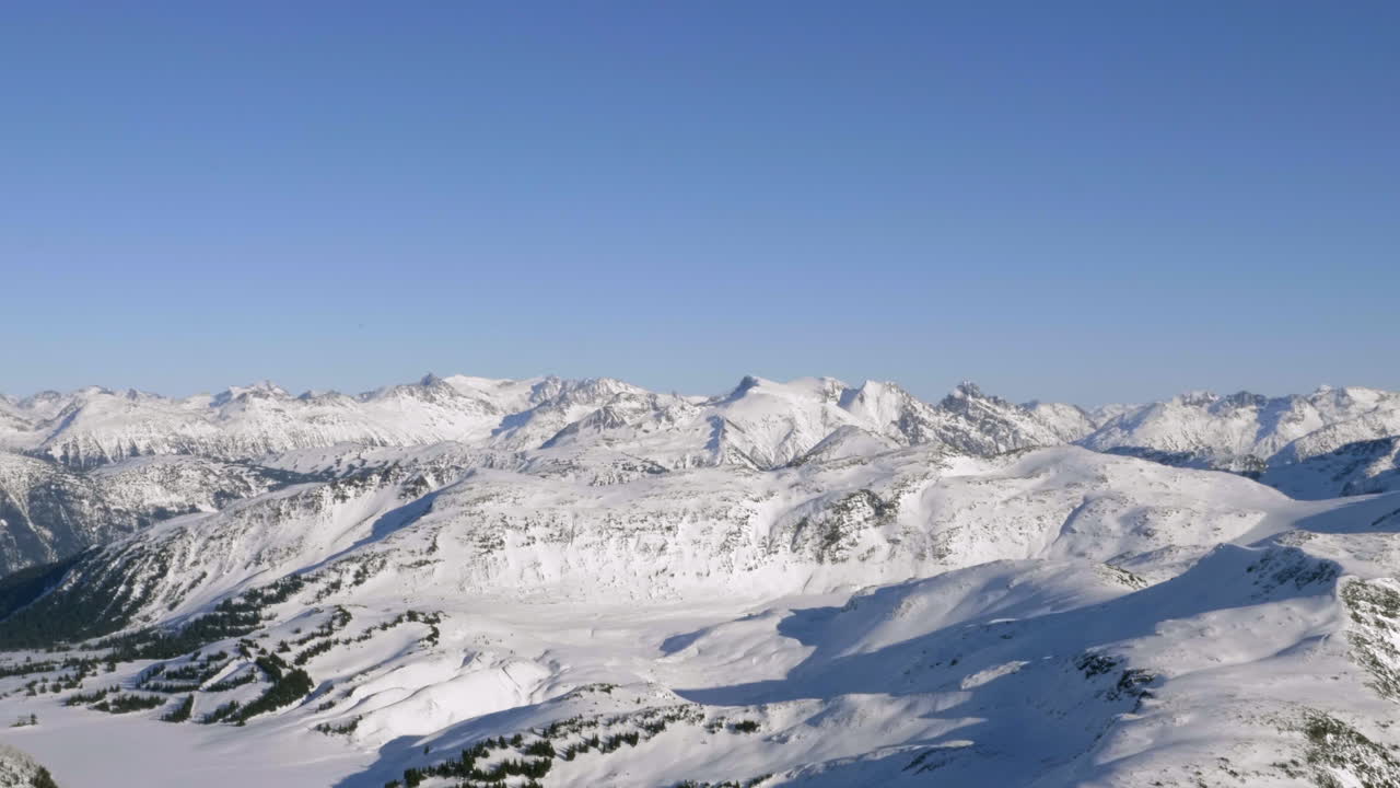 Sunlight Through Snowy Mountain Ridges Against Blue Clear Sky In Canada