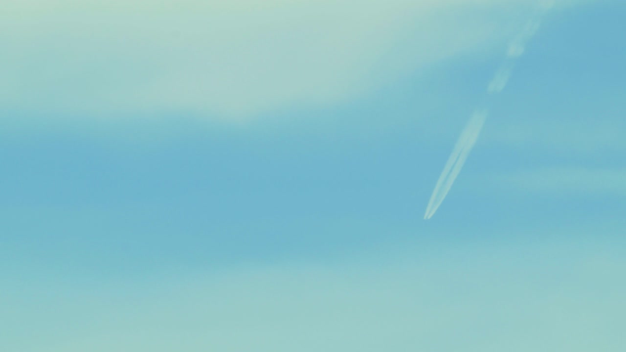 구름이 있는 푸른 하늘에 제트기의 흔적, 멀리서 중간 샷