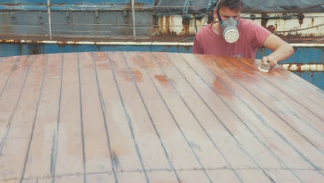 youth manually sanding boat roof planking